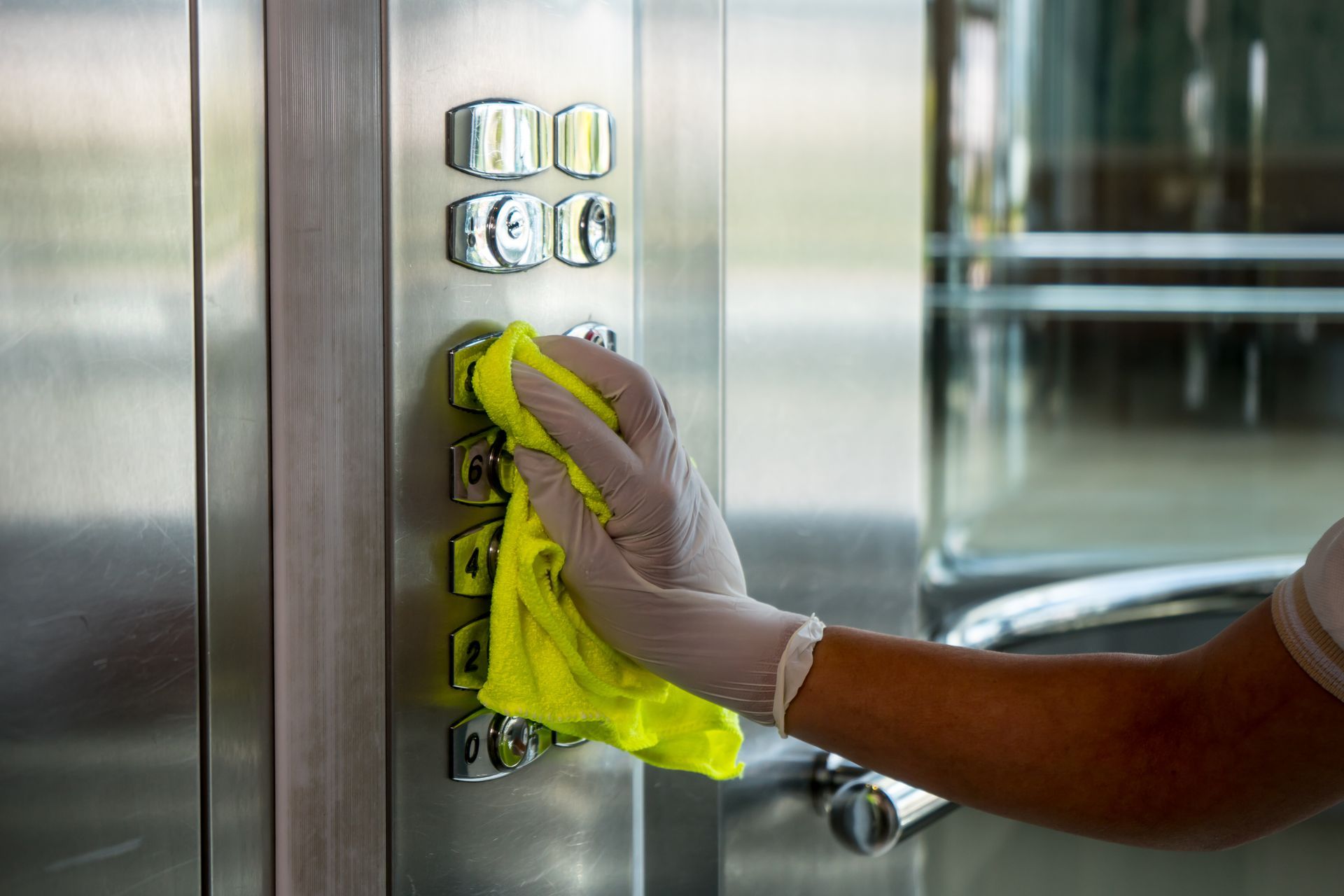Cleaning an elevator button with a cloth.