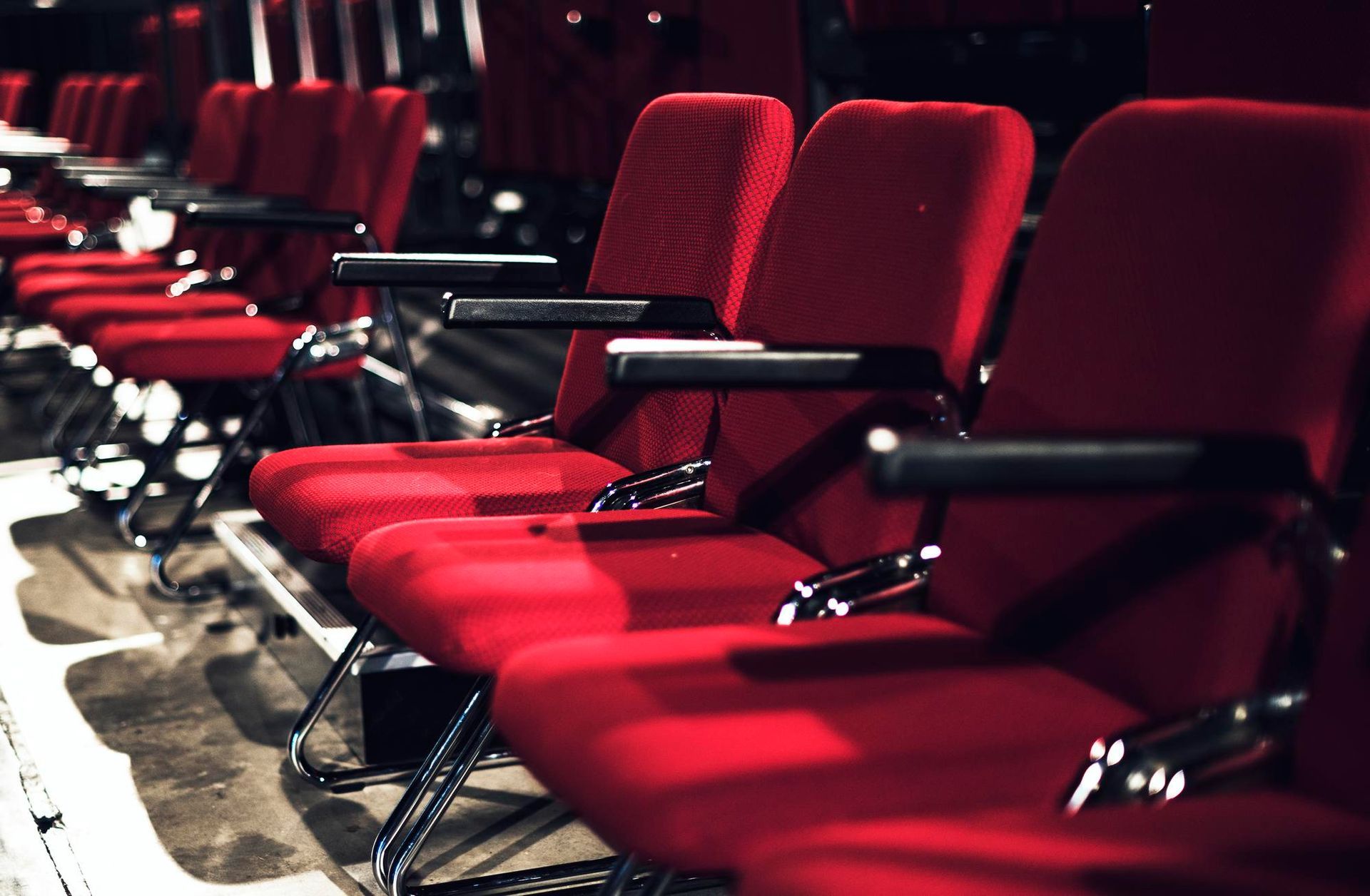 A row of red chairs are lined up in an auditorium.